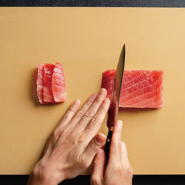 Kutting av fisk på et beige Parker Asahi-skjærebrett sett ovenfra – bruksbilde.